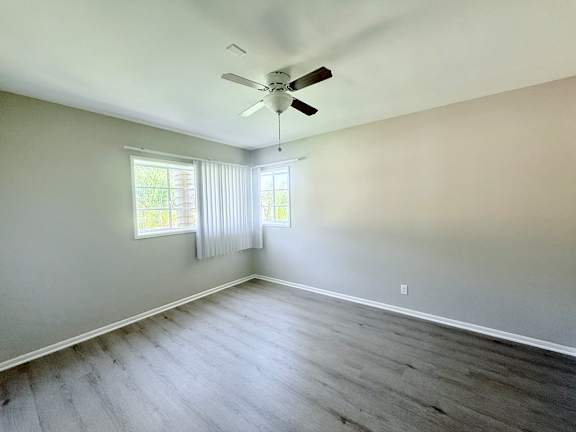 A room with a ceiling fan and a window with blinds.