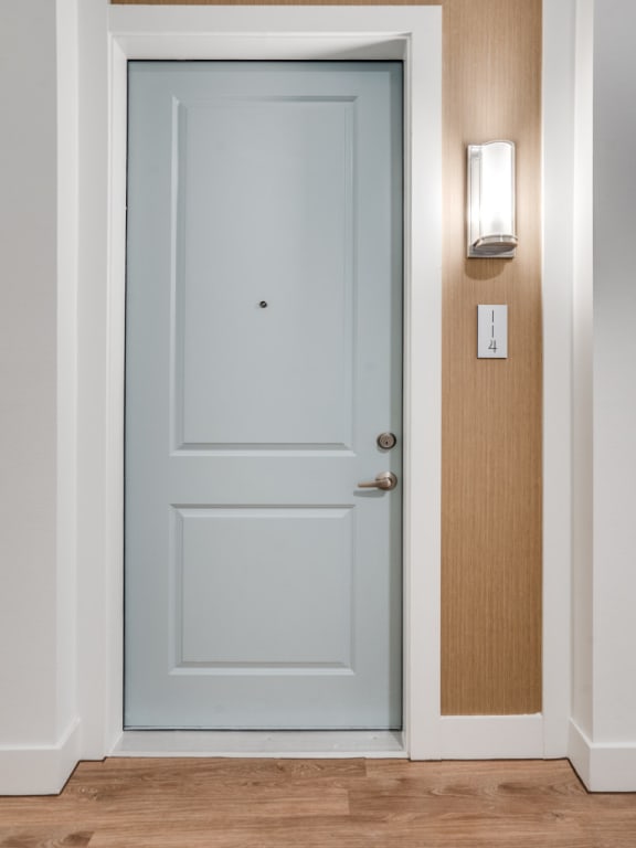 a light blue door with a wooden wall and a light switch