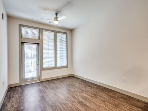 the living room of an empty home with wood flooring and a ceiling fan