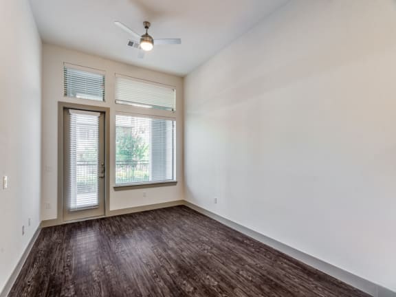an empty living room with a window and a ceiling fan