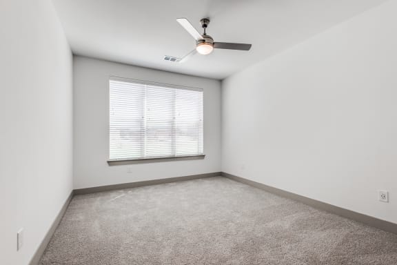 an empty room with a window and a ceiling fan