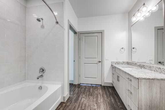 a white bathroom with a tub and shower and a sink
