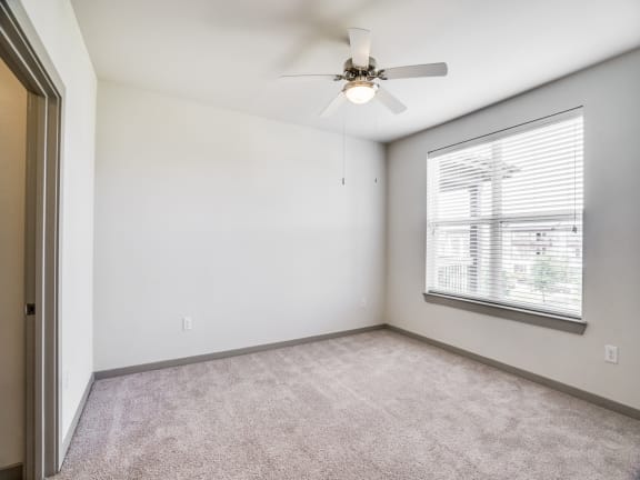 an empty living room with a ceiling fan and a window