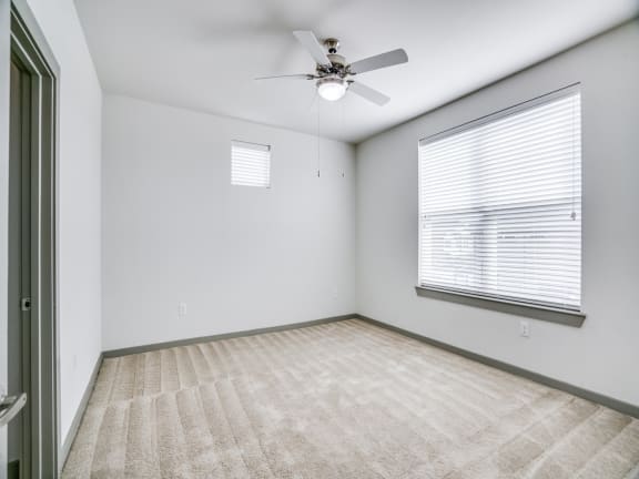 an empty living room with a ceiling fan and a large window