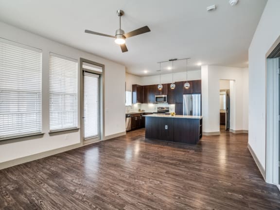 an empty living room and kitchen with a ceiling fan