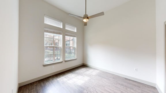an empty living room with white walls and a ceiling fan