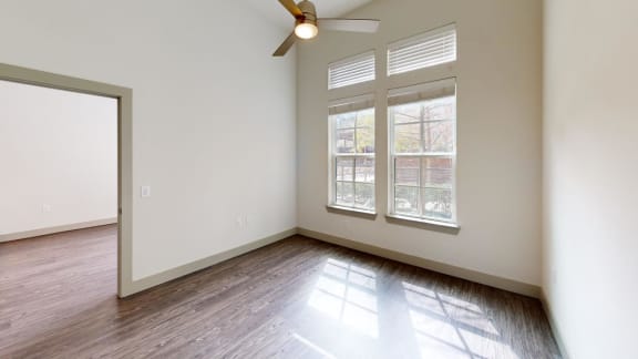 a living room with white walls and wood floors and a ceiling fan
