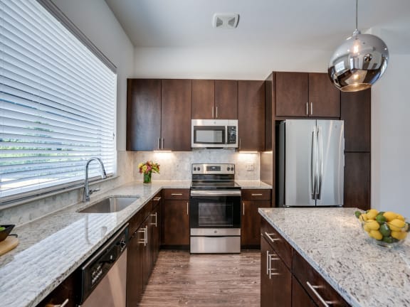 a kitchen with wooden cabinets and granite counter tops and stainless steel appliances