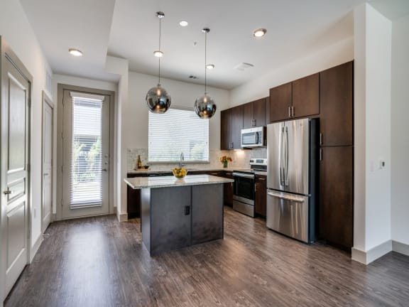 an empty kitchen with stainless steel appliances and wooden cabinets