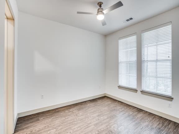 a bedroom with a ceiling fan and two windows