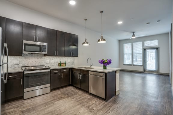 an empty kitchen with stainless steel appliances and dark wood cabinets