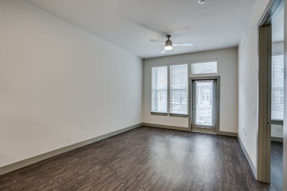the living room of an empty apartment with wood flooring and a ceiling fan