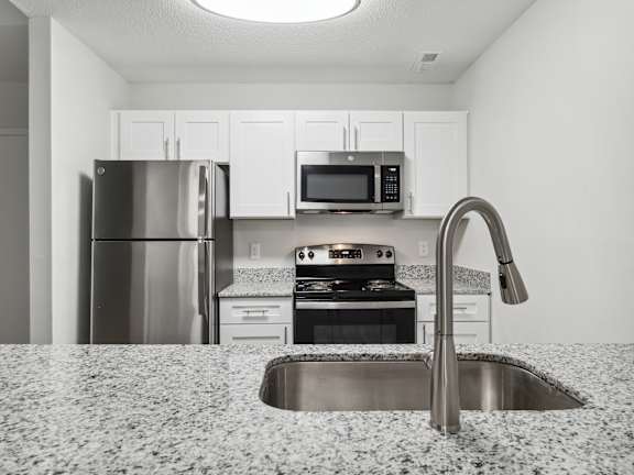 A kitchen with a sink, stove, and refrigerator.