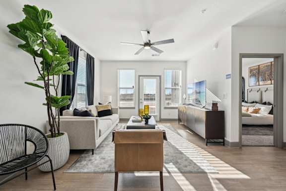 A living room with a white couch, a wooden table, and a ceiling fan.