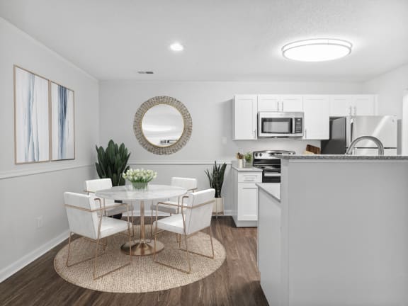 a dining area with a table and chairs and a kitchen in the background