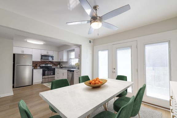 a kitchen and dining room with a white table and green chairs