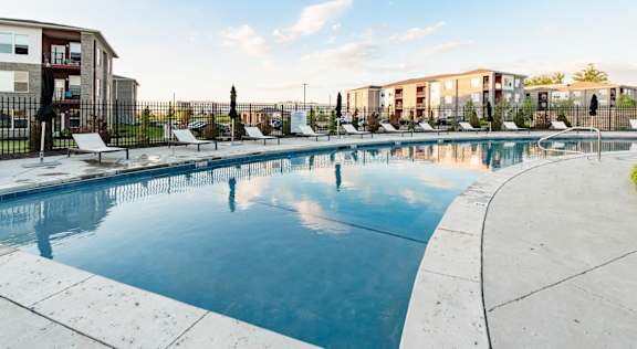 A large outdoor swimming pool with lounge chairs and a fence around it at Echo Park at Perry Crossing Apartments, Plainfield, IN, 46168