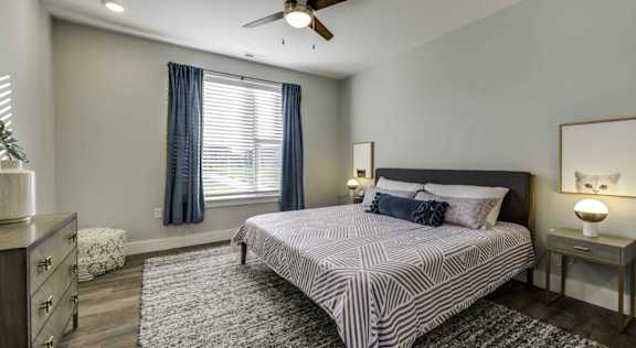A bedroom with a bed, nightstand, and a ceiling fan at Echo Park at Perry Crossing Apartments, Plainfield, Indiana