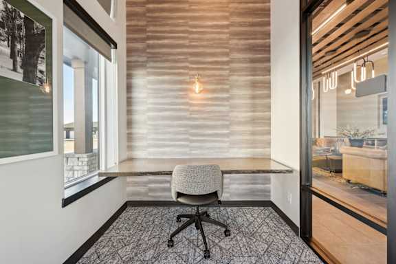 A room with a chair and a table with a window.