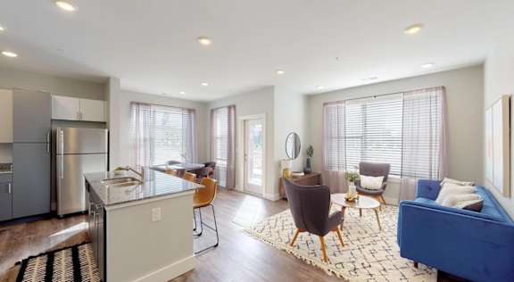 A modern kitchen with a blue couch in the living room. at Echo Park at Perry Crossing Apartments, Plainfield