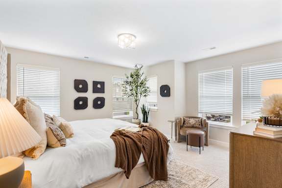 A bedroom with a large bed and a chair.