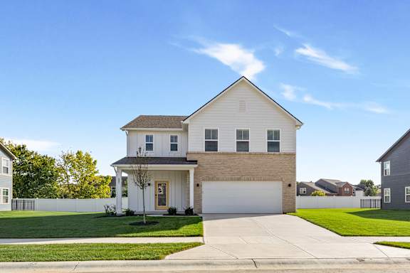 A white house with a brown roof and a garage door.