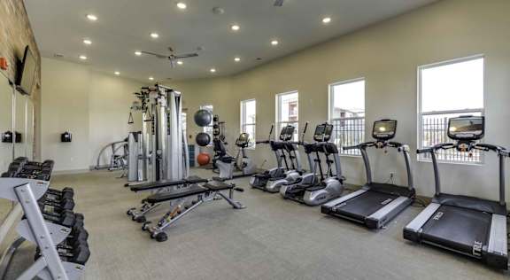 A spacious gym with a variety of equipment including treadmills, elliptical machines, and weight machines at Echo Park at Perry Crossing Apartments, Plainfield, Indiana