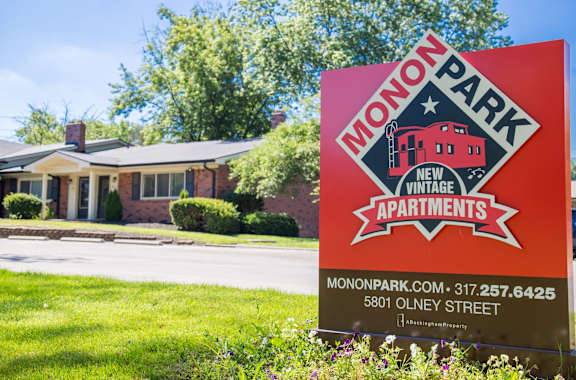 A sign for Monon Park New Vintage Apartments is displayed in front of a house.
