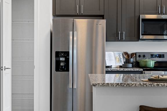 Kitchen at Nook Nine with stainless steel refrigerator, granite countertops, and spacious pantry.