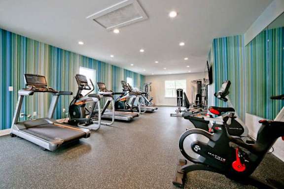 A gym with a variety of exercise equipment including treadmills, stationary bikes, and elliptical machines at Gramercy Apartments, Carmel Indiana