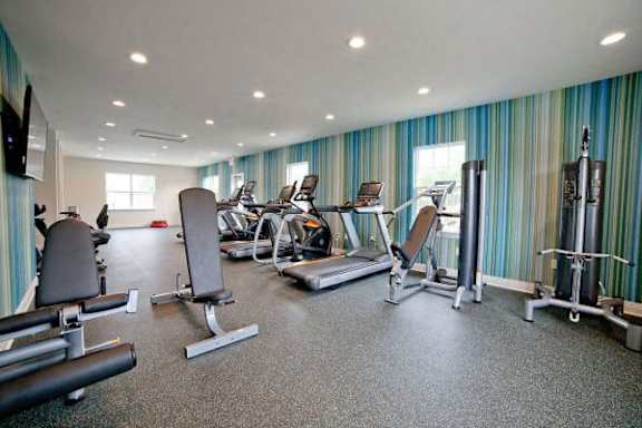 A gym with a variety of equipment including treadmills, weights, and exercise machines at Gramercy Apartments, Carmel, IN