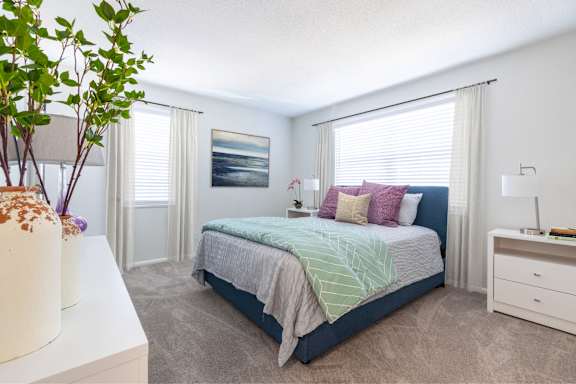 A bedroom with a bed, nightstand, and a plant at Gramercy Apartments, Carmel, IN