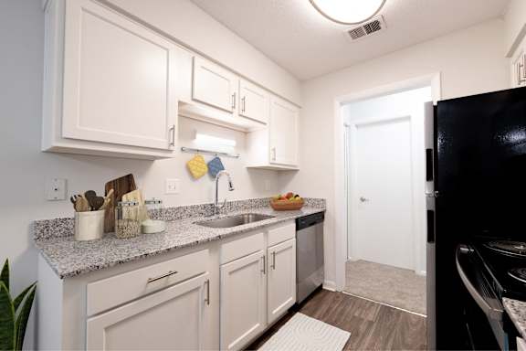 A kitchen with white cabinets and a black refrigerator at Gramercy Apartments, Carmel Indiana