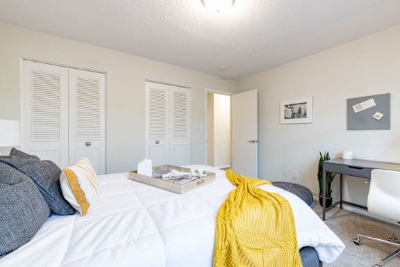 A bedroom with a white bed and a yellow blanket at Gramercy Apartments, Carmel, 46032