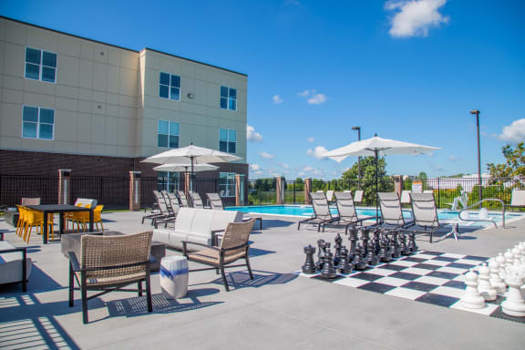 a chess set on a chess board in front of a swimming pool and a building at The Century at Purdue Research Park-Student, West Lafayette