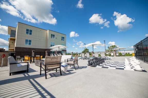an outdoor patio with tables chairs and umbrellas and a building at The Century at Purdue Research Park-Student, Indiana, 47906