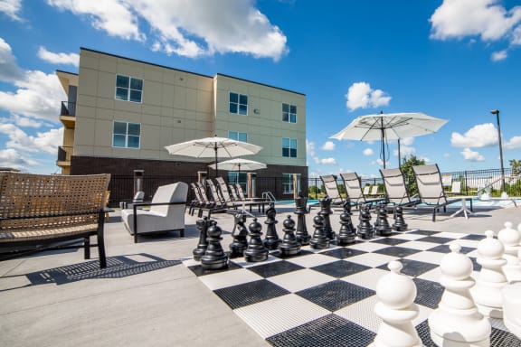 a chess board on a patio with chairs and umbrellas at The Century at Purdue Research Park-Student, West Lafayette Indiana