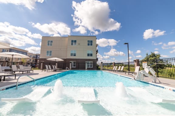 a swimming pool with a fountain in front of a building at The Century at Purdue Research Park-Student, West Lafayette, IN 47906