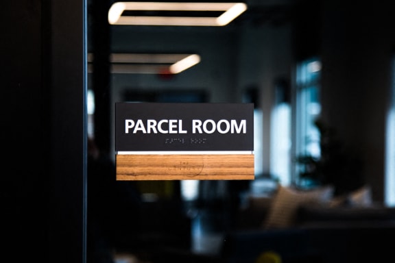 a parcel room sign hanging on a door at The Century at Purdue Research Park-Student, West Lafayette Indiana