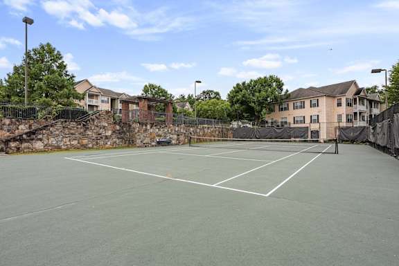 A tennis court surrounded by a stone wall and a fence at Village at Almand Creek, Georgia