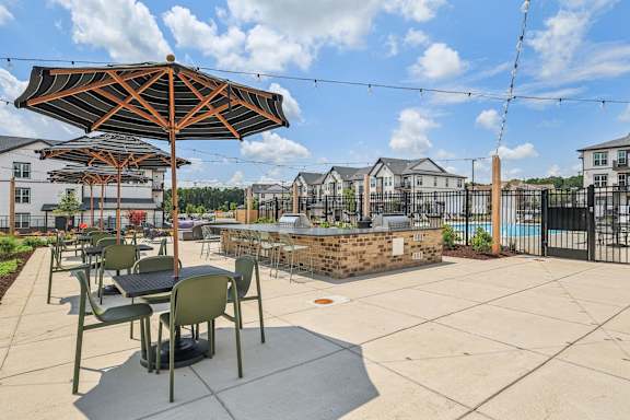 an outdoor patio with tables and umbrellas and a pool at Nook Nine, Indianapolis, 46240