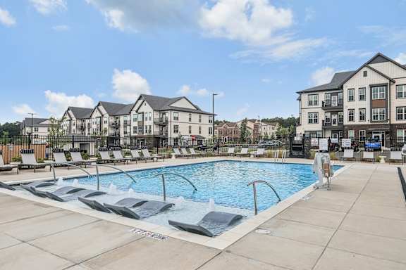 a swimming pool with lounge chairs in front of an apartment building at Nook Nine, Indianapolis, 46240