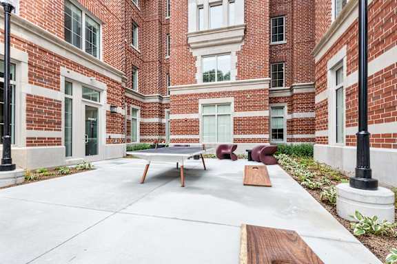 A courtyard with a table and chairs in front of a brick building.