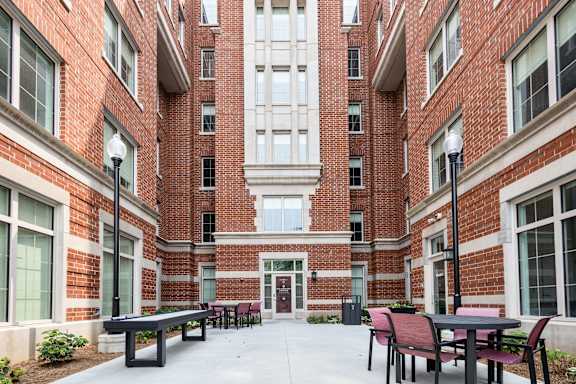 A courtyard with tables and chairs surrounded by brick buildings.