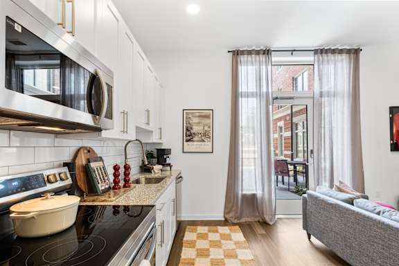 A kitchen with a black stove top and white cabinets.