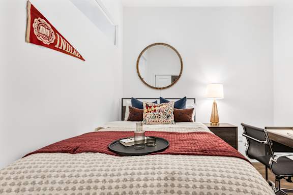 A bedroom with a bed, chair, and a wall hanging.