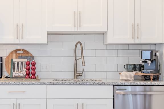 A kitchen with white cabinets and a marble countertop.