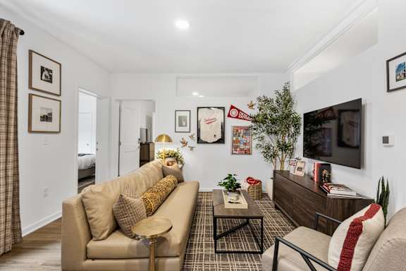 A guest suite living room with couch, coffee table, mounted TV, credenza, arm chair and decor.