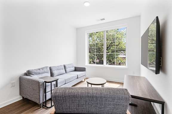 A grey couch with a white pillow is in the living room.