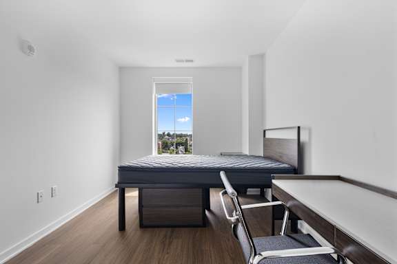 A bedroom with a bed, chair, and a window.
